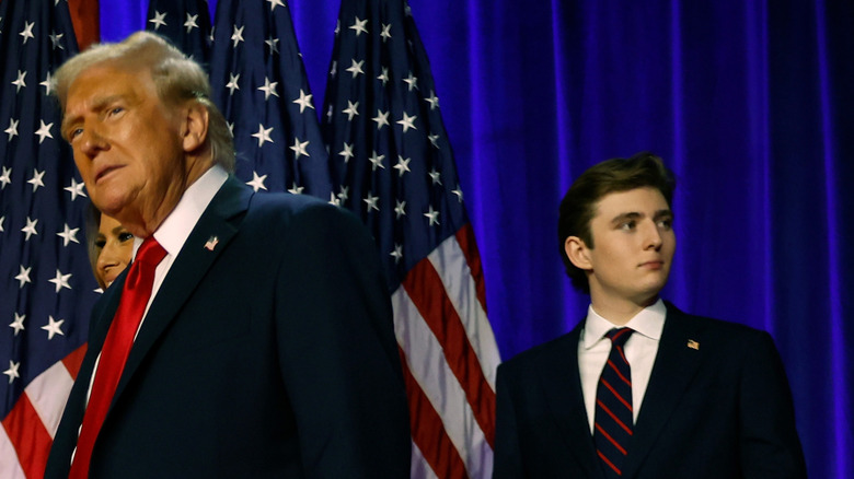 Donald Trump walking in front of Barron Trimp on stage surrounded by U.S. flags