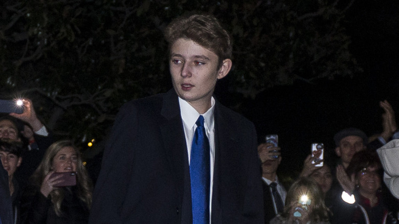 Closeup of Barron Trump outside at night surrounded by fans