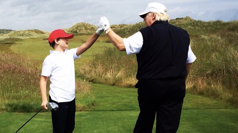 Barron Trump and Donald Trump high-fiving on golf course