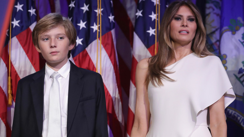 Closeup of Barron and Melania Trump on stage surrounded by U.S. flags