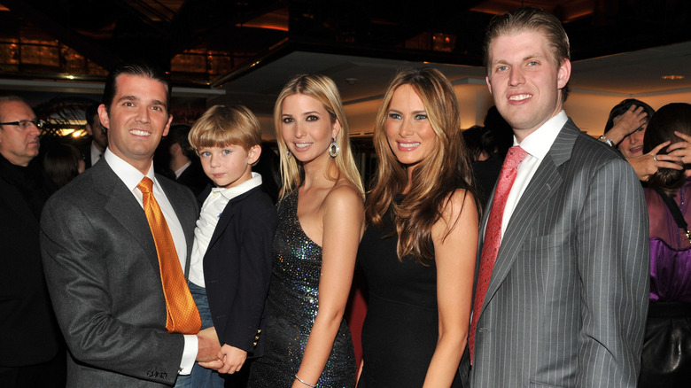 Donald Trump, Jr. holding an infant Barron Trump with Ivanka Trump, Melania Trump, and Eric Trump posing next to them