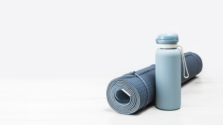 Rolled yoga mat next to a water bottle