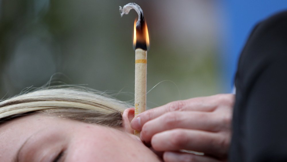 Woman receiving ear candle therapy