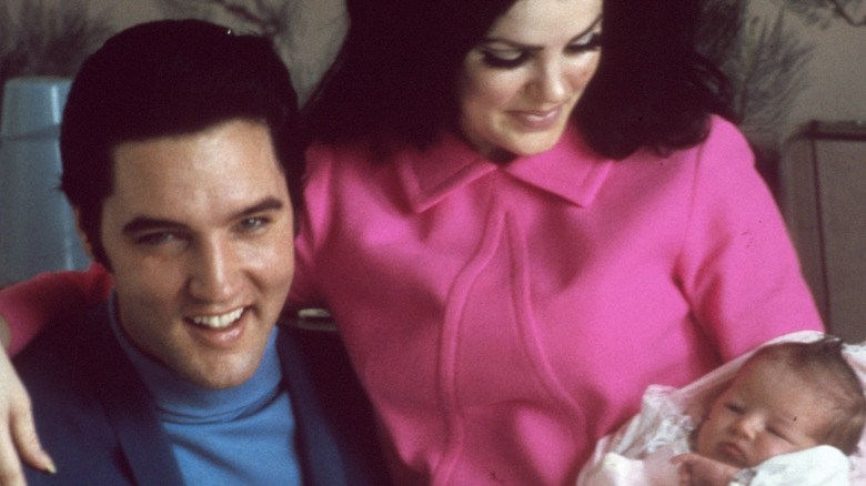 Priscilla Presley in pink coat with baby