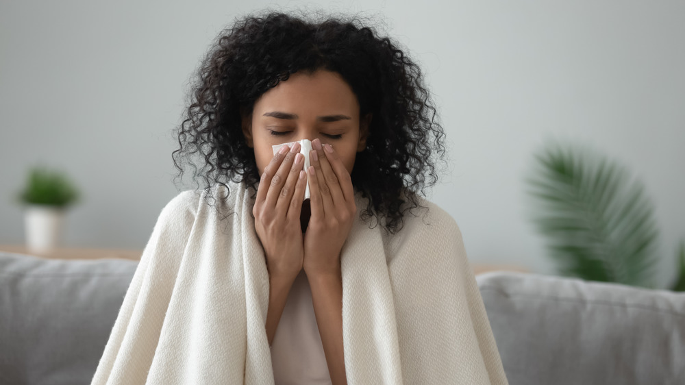 Woman sick blows her nose into a tissue