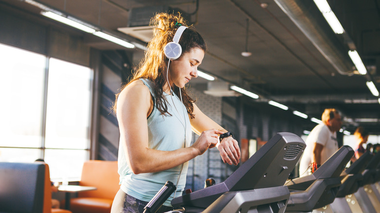 Woman checking her fitness tracker while on the treadmill