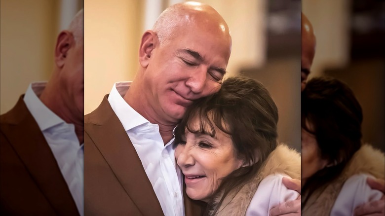Jeff Bezos wearing a brown suit while hugging his mom who's wearing a white coat.