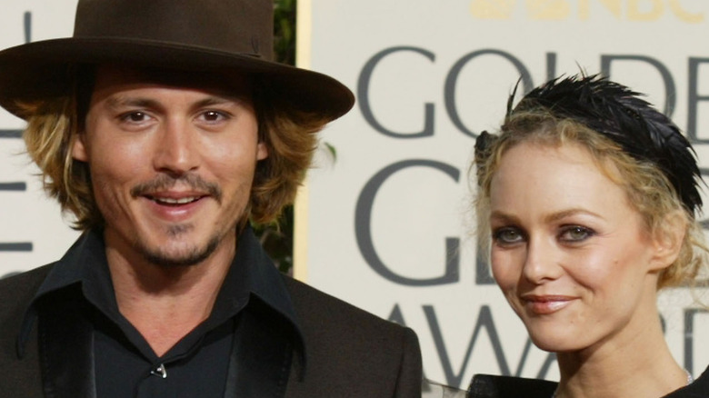 Johnny Depp (in a hat) poses with Vanessa Paradis (smiling)