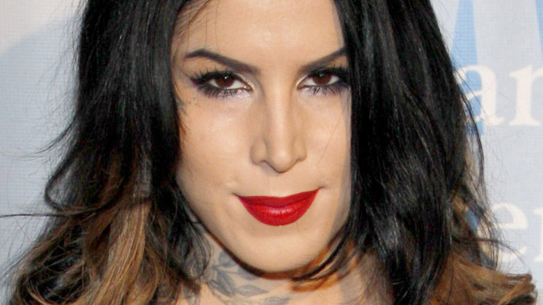 Kat Von D head tilted down grinning in red lip