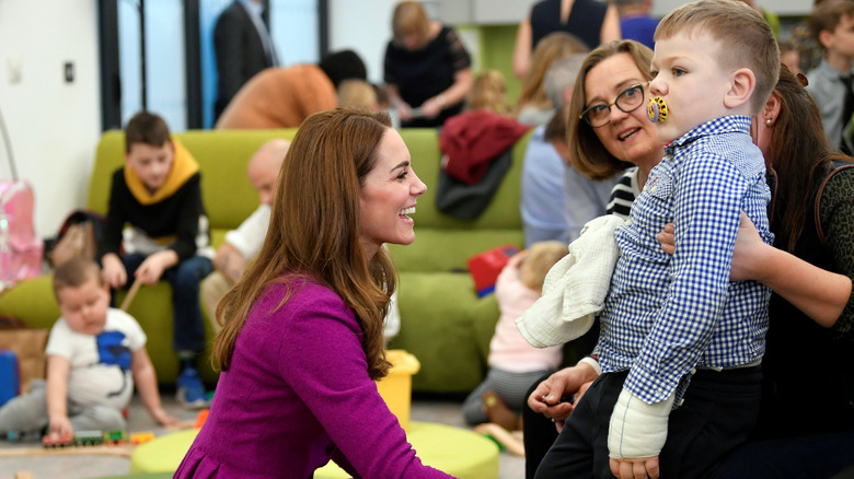 Kate Middleton smiling at child, crouching