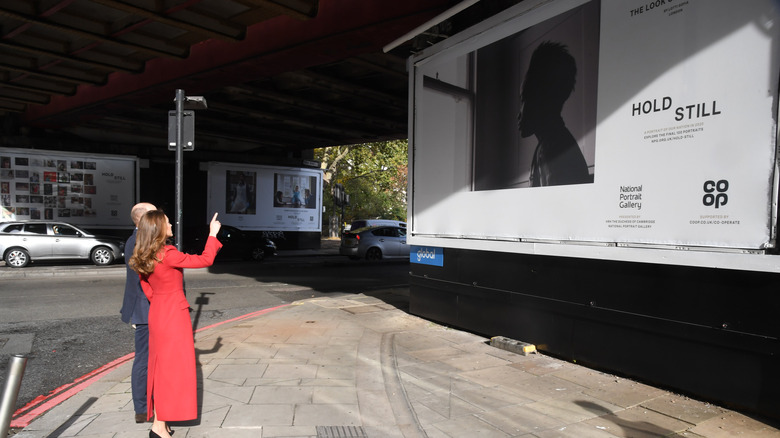 Kate Middleton and Prince William pointing at billboard