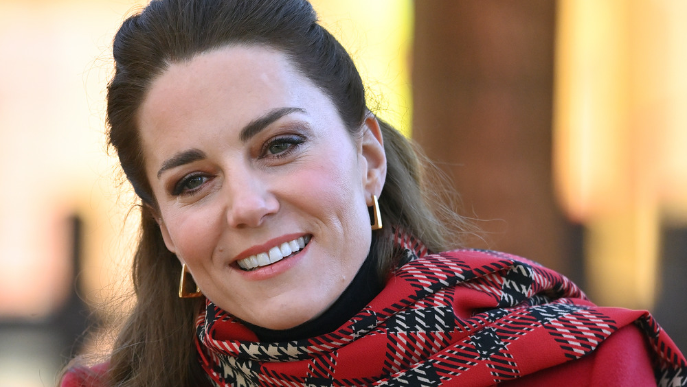 Kate Middleton smiling in a plaid coat