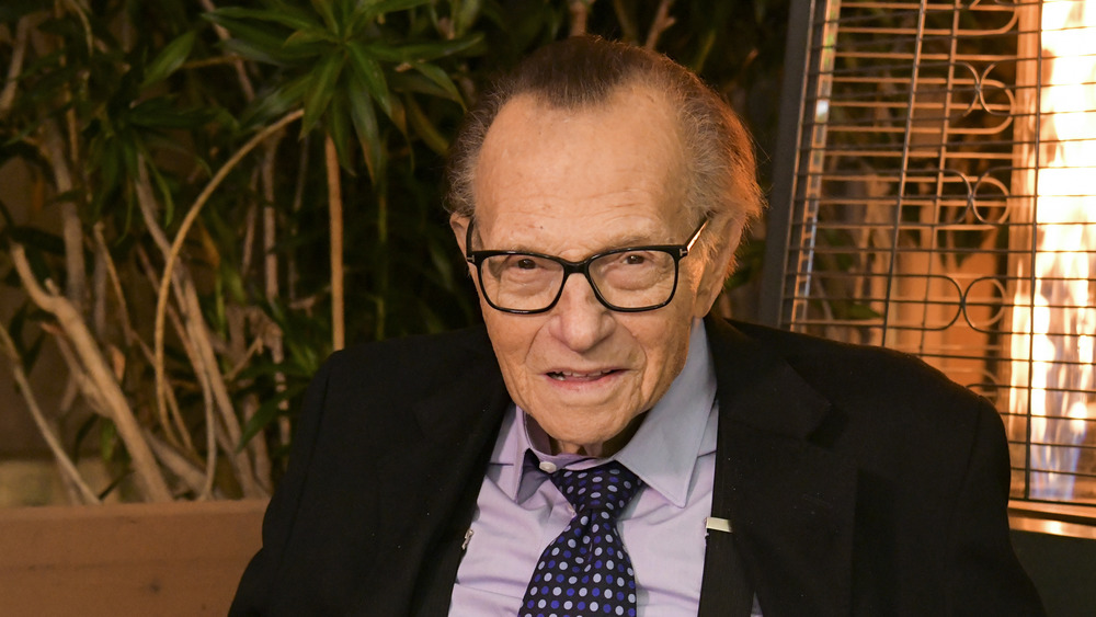 Larry King in front of plants