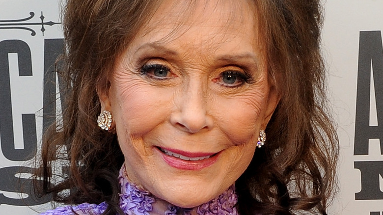 Loretta Lynn smiling in a purple dress