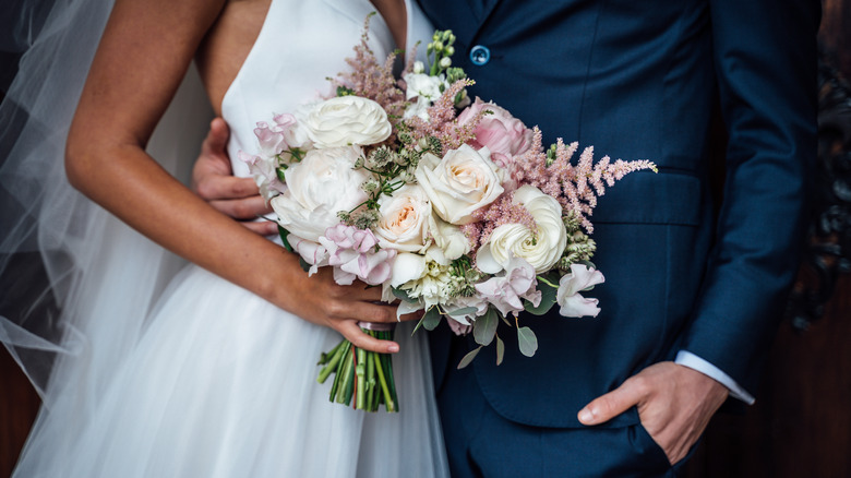 Woman holding a bouquet of flowers next to man