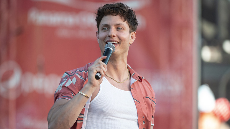 Matt Rife holds a mic on stage smiling