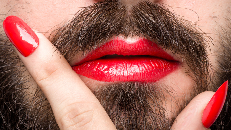 Bearded face with red lipstick, red nail polish