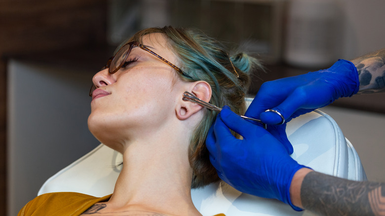 Woman getting ear pierced 