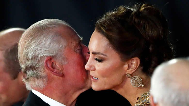 King Charles III kisses Kate Middleton at an event.