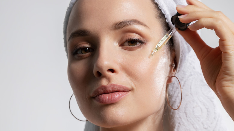 Woman smiling and applying facial serum