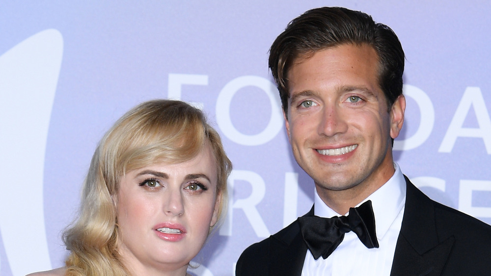 Rebel Wilson, Jacob Busch smiling at formal event