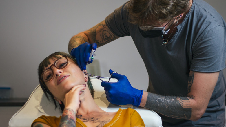 Woman getting her ear pierced