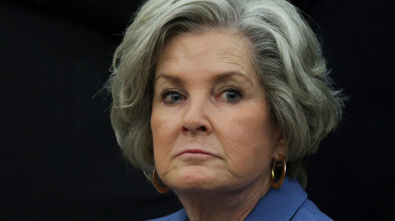 Susie Wiles looking serious in a blue top and gold hoop earrings