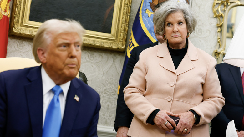 Susie Wiles staring down Donald Trump in a peach jacket with a black top underneath it