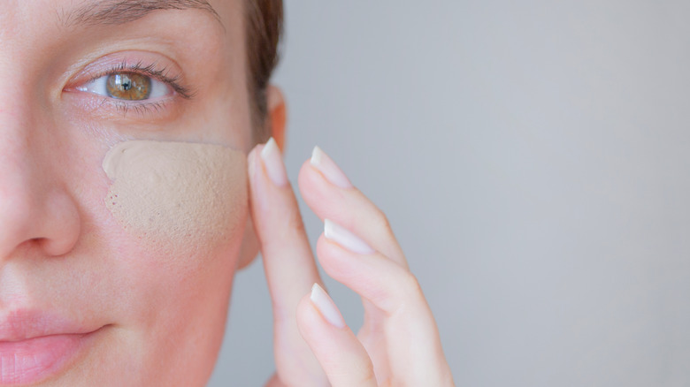 A woman putting on tinted moisturizer 