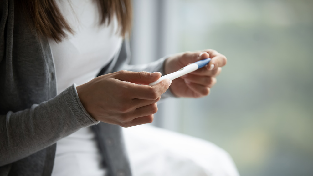 woman holding pregnancy test stick