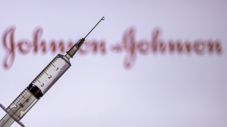 Vaccine syringe in front of Johnson & Johnson sign