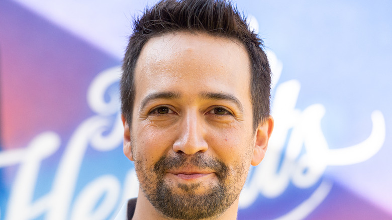 Lin Manuel Miranda in front of an "In the Heights" sign