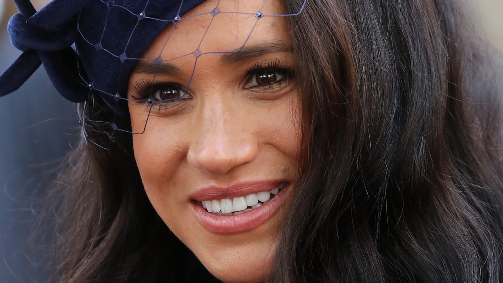 Meghan Markle smiling, wearing hat