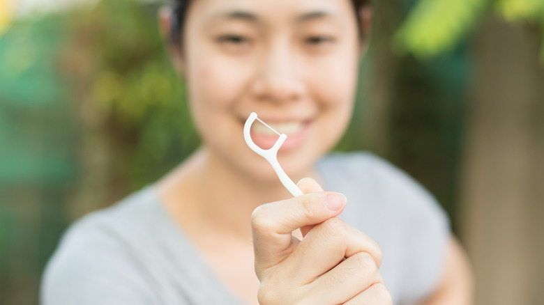 Woman smiling and holding a floss pick