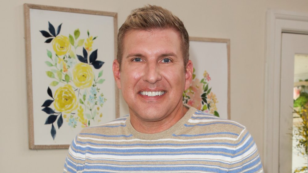 Todd Chrisley in front of paintings of flowers