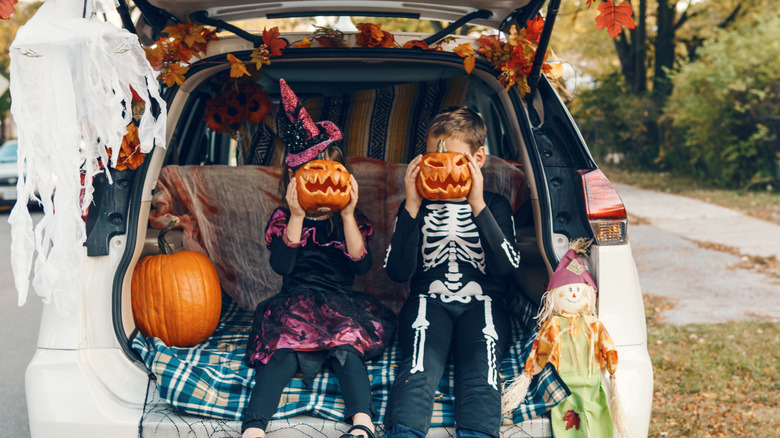 Kids posing in the back of a car decorated for Halloween