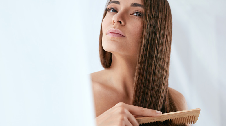 woman brown hair combing hair through 