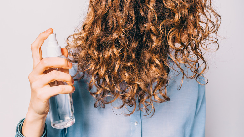 woman spraying product in her hair