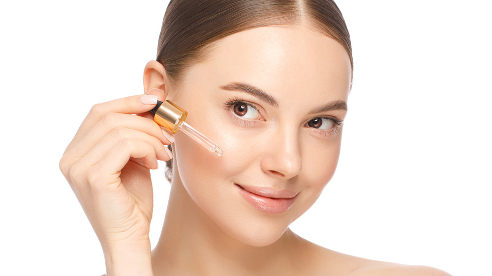 Woman applying serum to face