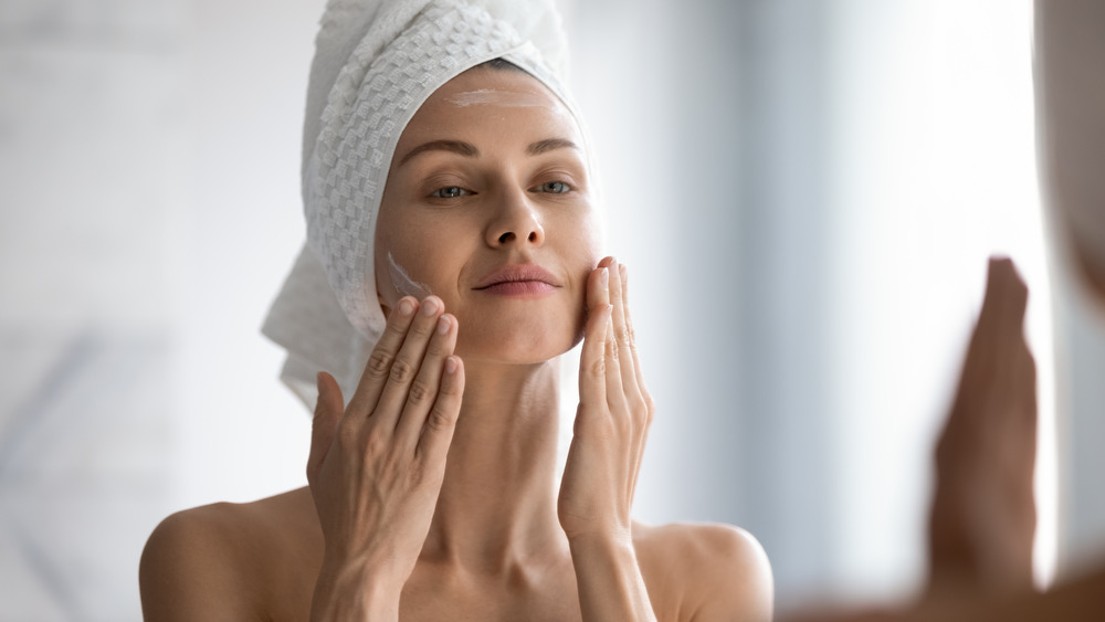 Woman applying cream on face