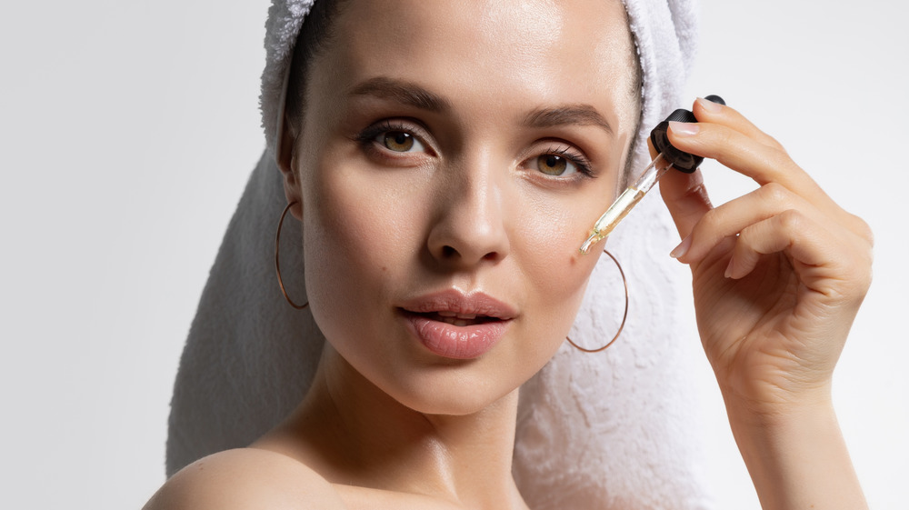 Woman applying serum on face