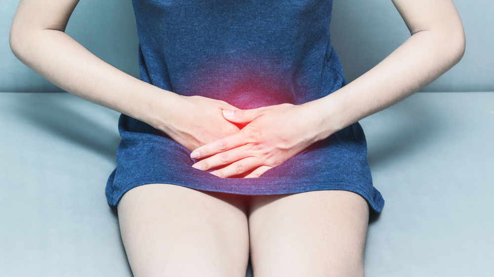 A woman with her hands over her lower abdomen 