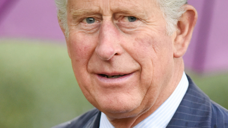 Prince Charles outside with umbrella