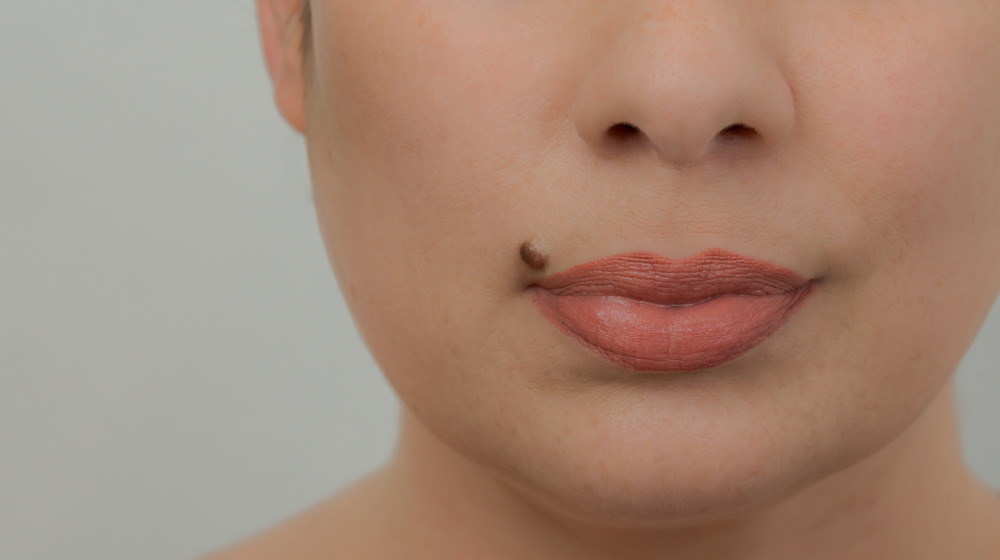 Woman with a beauty mark near her full pink lips