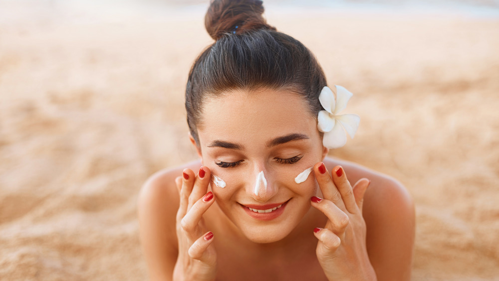 A woman applying sunscreen at the beach