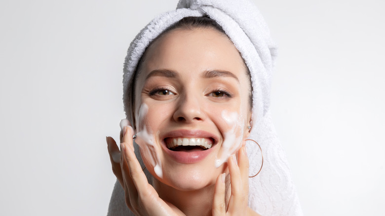 Woman cleaning face with towel on head