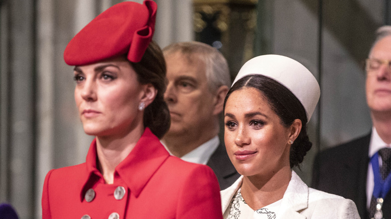 Kate Middleton standing in front of Meghan Markle