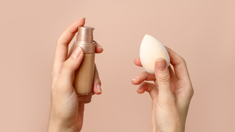 Hands holding foundation and makeup sponge