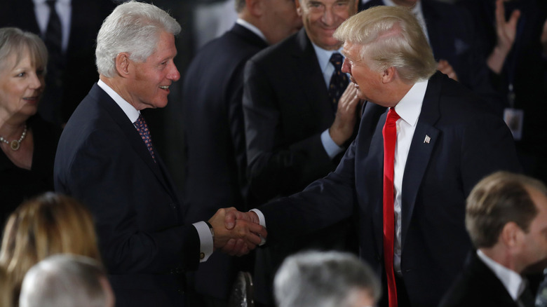 Bill Clinton and Donald Trump shaking hands in suits