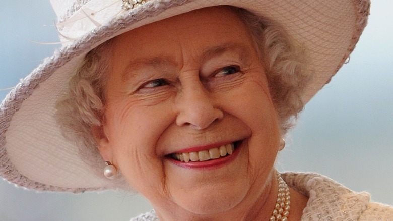 Queen Elizabeth II smiling in an all-white outfit